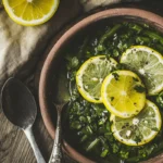 Freshly sautéed green beans with garlic butter, garnished with lemon slices and black pepper in a rustic bowl.